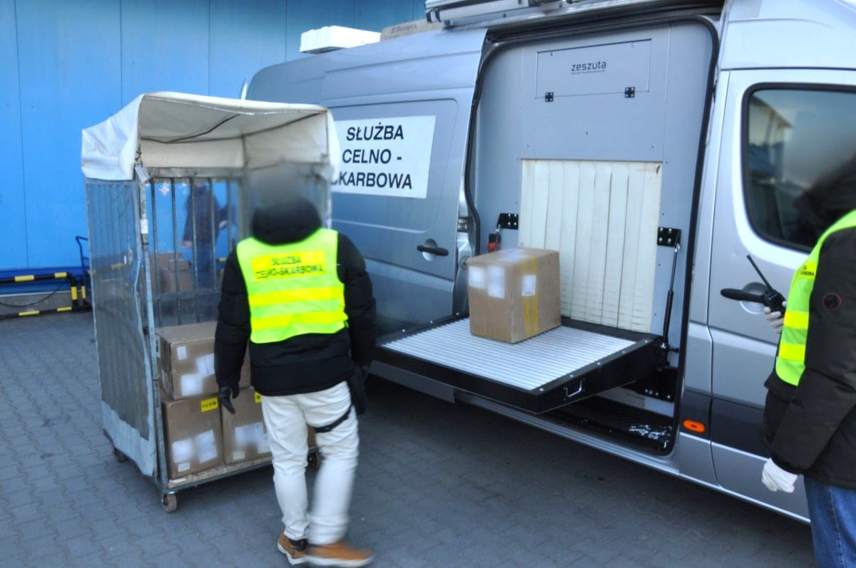 Funkcjonariusz celny konfiskujący paczkę z e-papierosami, symbolizujący zatrzymanie i utylizację nielegalnych produktów.