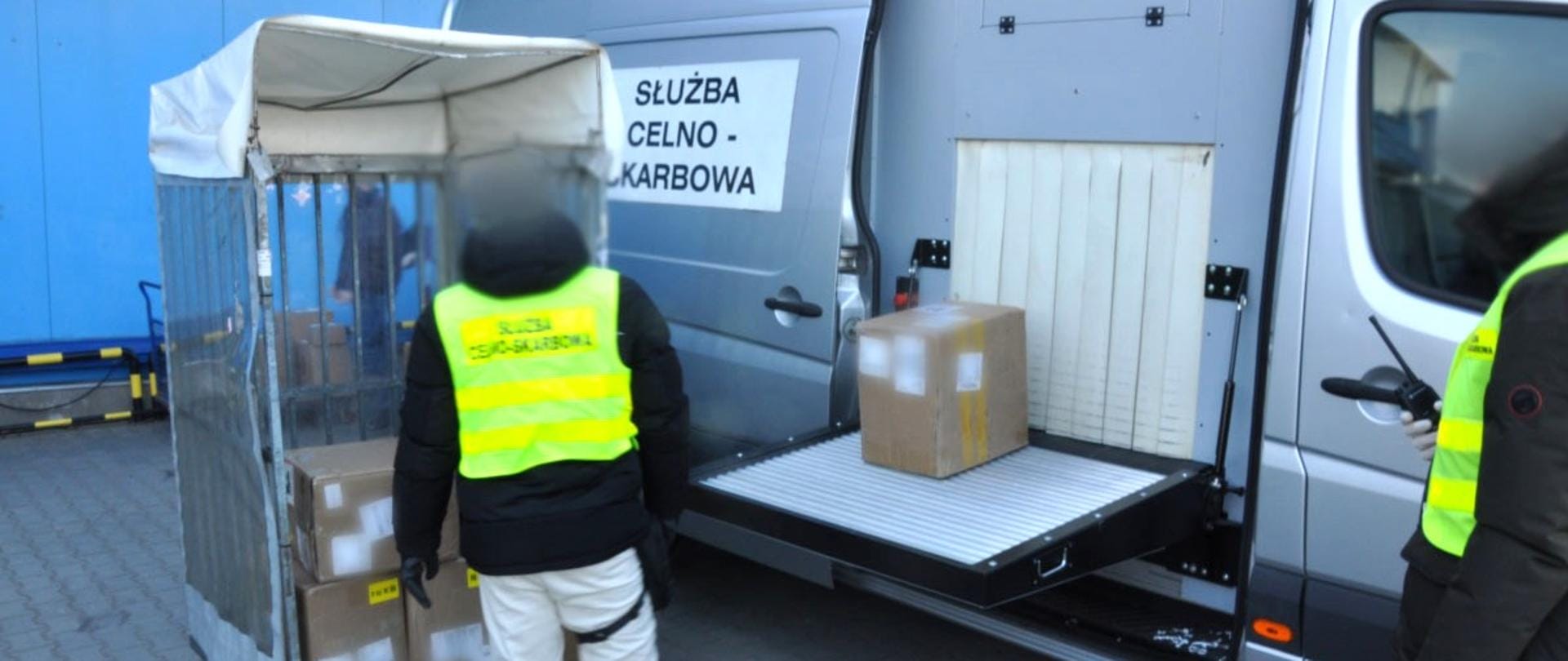 Otwarta paczka, w której pod warstwą innych przedmiotów ukryte są e-papierosy, z dokumentami celnymi leżącymi obok, symbolizująca fałszowanie deklaracji celnych.