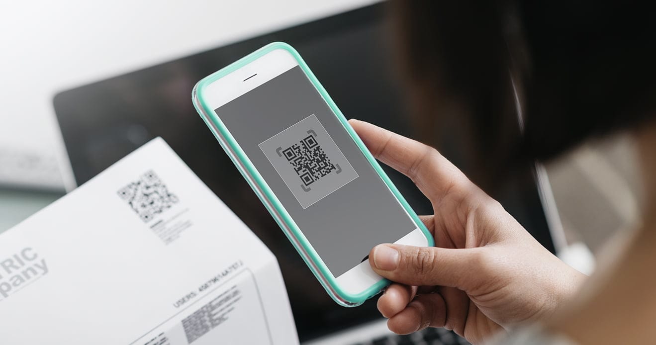 Osoba skanująca kod QR na opakowaniu e-papierosa jednorazowego za pomocą smartfona, z widoczną zdrapką na etykiecie.