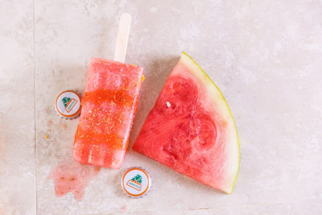 Graficzna reprezentacja e-papierosa z chmurą pary, obok świeżych truskawek i melona, symbolizująca popularność smaku Strawmelon w branży vape.